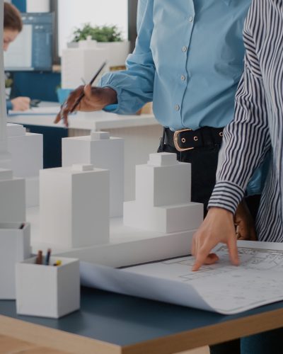 Close up of diverse team of women working on blueprints design in office. Multi ethnic architects using industrial print on table to plan construction layout for architecture project.